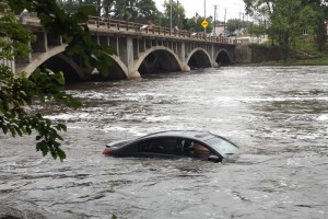 A car remained partially submerged as Fox River waters rushed around it in North Aurora at mid-week. (Suburban Chronicle photo)