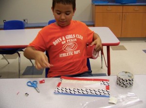Aidan Mulcahey gets into the duct tape to finish off his homemade pencil pouch during the back-to-school craft session at the Pekin n Public Library on Aug. 18.  The kids made their own pencil cases from plastic storage bags and duct tape. (Photo courtesy of Pekin Public Library) 