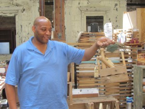 : Bryant Williams, senior director of Rebuilding Exchange, holds tools made from repurposed wood that are part of the reuse warehouse's RX line. Rebuilding Exchange was the first reuse center in Cook County. (Photo by Kevin Beese/For Chronicle Media)