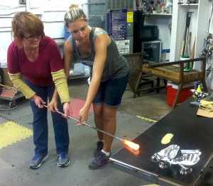 Meredith Caudill of Pekin (left) and Jeremie Draper, owner of JDraper Studios, shape and roll glass on a marver table. Caudill and her husband, Chuck, had reserved studio time for a date night to learn the art of blowing glass.