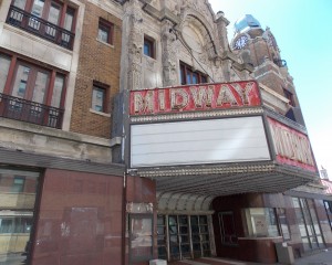 The exterior of the Midway Theater on State Street shows peeling paint, a partly broken facade and dirt-streaked windows. 