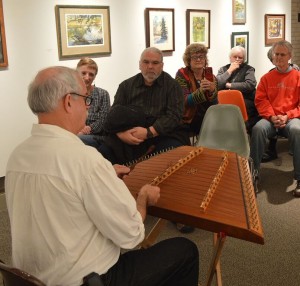 Dale C. Evans, an artist and luthier, gives a stringed folk instrument demonstration recently in the McLean County Arts Center’s Armstrong Gallery. Evans’ painting exhibition, Corner of my Eye, continues in the gallery through Jan. 2. (Courtesy of the McLean County Arts Center)