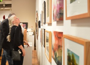 Visitors to the McLean County Arts Center’s recent Holiday Treasures open house admire artwork in the gallery. The Holiday Treasures fine art and seasonal gifts display will continue through Jan. 2. (Courtesy of the McLean County Arts Center) 