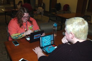 Leisl Prentice (left) and Amanda Doyle, reference librarians at the Peoria Public Library, play a game of Battleship during the first session of a new program they’ve created called Play to Innovate that’s designed to help adults be more creative at their jobs. (Photo by Elise Zwicky)