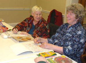 Deb Beschorner (left) of Germantown Hills and Peggy Hinz of Flanagan laugh as they color at a recent adults-only coloring night at the Eureka Public Library. Both women said they find the craft calming. (Photo by Elise Zwicky)
