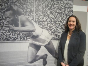 Illinois Holocaust Museum curator Arielle Weininger with a photo of Jesse Owens at the entrance of the Berlin Olympics exhibit.