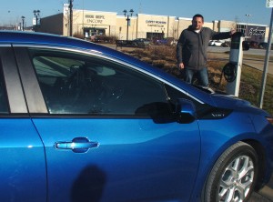 David Nichols of Yates City stands next to his 2016 Chevy Volt, one of three electric cars he’s owned or leased since 2011. Nichols commutes 53 miles daily to work in Peoria and frequently uses the public charging stations in the area to “top off” his car’s charge. 
