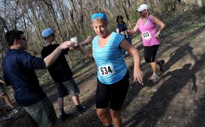 Brothers Ethan and Julian Heidrick hand out water to runners Toni Sawilchik (534) and Michelle Parrish (533) in the middle of the woods during the Saw Wee Kee Spring Trail Challenge at Saw Wee Kee Park in Oswego on Saturday, April 16, 2016. Photo by Steven Buyansky