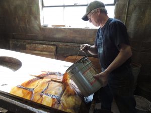 Phil Nelson of Rockford Finishing uses the stripping tank to pour chemicals over a door to be refinished. (Photo by Lynne Conner/for Chronicle Media)