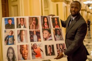 A poster displays faces of gun victims in Cook County held by a staff member of Congresswoman Robin Kelly of Chicago. (Photo courtesy Rep. Robin Kelly Twitter)