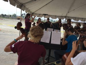 Members of the Argo High School string orchestra perform at the school’s arts center groundbreaking with construction equipment behind them. (Chronicle Media)