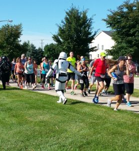 A Storm Trooper cheers on runners as they take off from the starting line during this years annual Blues on Barton 5K charity run in Oswego's Churchill subdivision on Aug. 6. (Photo by Erika Wurst/for Chronicle Media) 