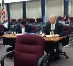 Lake County Coroner Dr. Thomas Rudd (seated at right) waits for the July 14 hearing of county's Electoral Board of Review to begin. (Photo by Gregory Harutunian/for Chronicle Media)