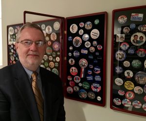 Dr. David Parkyn stands by his wall of collected presidential campaign buttons of losing candidates.   
