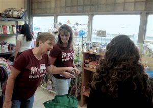 Moms Who Care founder Barb McDonald, right, and volunteer Jan Sheldon, encourage an East Peoria Community High School student to pick up a few snacks before heading back to class. (Photo by Holly Eltenmiller / for Chronicle Media)