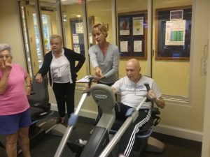 Leo Gallan, 91, works out on the NuStep exercise machine during The Vi retirement community’s triathlon in Glenview as Vi personal trainer Viviane Clemens stands behind him and monitors his progress. (Photo by Kevin Beese/for Chronicle Media) 