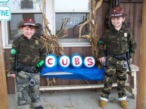 Field pumpkins decorated to represent the World Champion Chicago Cubs are being guarded by a pair of Jr. Illinois Conservation Police Officers outside a rural business in Mossville (Peoria County) on Halloween. (T. Alexander photo)