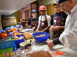 Right, Zach Selch of Evanston, chef/site supervisor, demonstrates how to make leftover turkey holiday sandwiches for sack lunches. From left are volunteers Max Greenberg Winnick, 10, of Evanston, Jacques Philippe, 10, of Evanston and Aden Rabinowitz, 13, of Wilmette. Images from Nov. 23, 2016 at the Thanksgiving-themed soup kitchen at Beth Emet The Free Synagogue in Evanston, 1224 Dempster St. (Photo by Karie Angell Luc/for Chronicle Media)   
