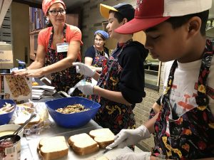 Left, Leslie Shulruff of Evanston, soup kitchen chair, demonstrates sack lunch packing. From right are Jacques Philippe, 10, of Evanston, Aden Rabinowitz, 13, of Wilmette and Donna Wolf of Evanston. Images from Nov. 23, 2016 at the Thanksgiving-themed soup kitchen at Beth Emet The Free Synagogue in Evanston, 1224 Dempster St. (Photo by Karie Angell Luc/for Chronicle Media) 