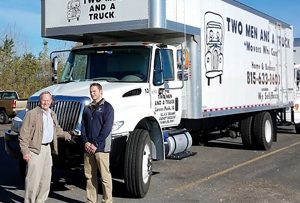 Army veteran Bob Christensen (left) and his son, Cory, stand in front of one of their Two Men and a Truck vehicles in Rockford. The two also own franchises in Peoria and the Quad Cities. Finding veterans like Christensen to become franchise owners is part of the company’s development plan. (Photo courtesy of Bob Christensen)