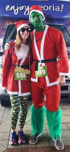 All registered participants in the Santa Cause 5K will receive a five-piece Santa suit, but participants are welcome to enhance their outfits as this couple did last year, dressing up as the Grinch, according to Kaci Osborne, the Peoria Area Convention and Visitors Bureau’s community development manager and race coordinator. (Photo courtesy Peoria Area Convention and Visitors Bureau)  